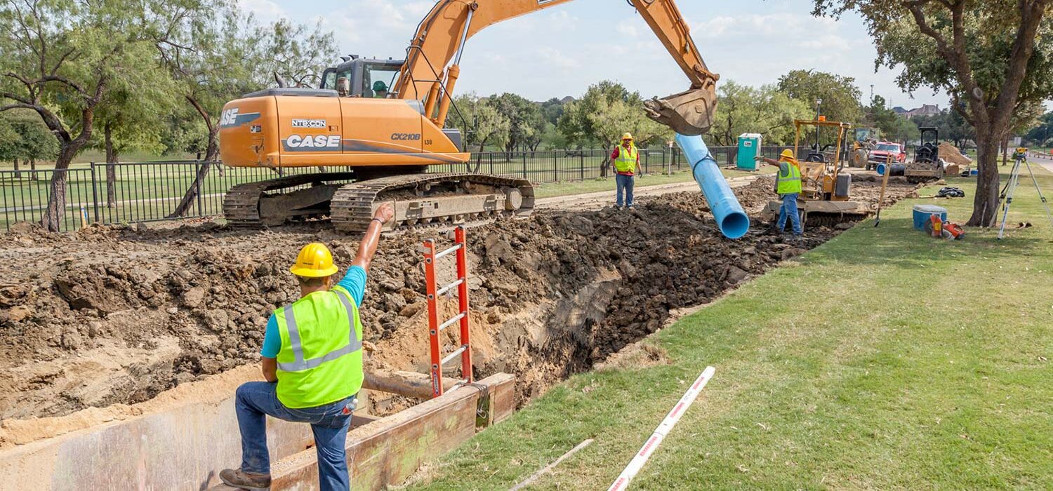 crew member directing excavator digging and team at Rochelle Blvd