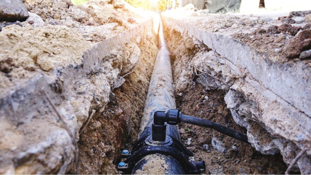 An exposed water pipe in the ground from digging and construction on land development